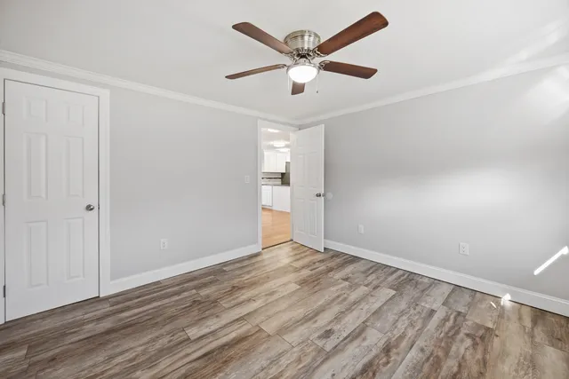 an empty room with wooden floor and a ceiling fan