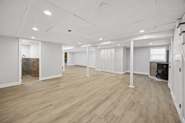 a view of an empty room with wooden floor fireplace and a window