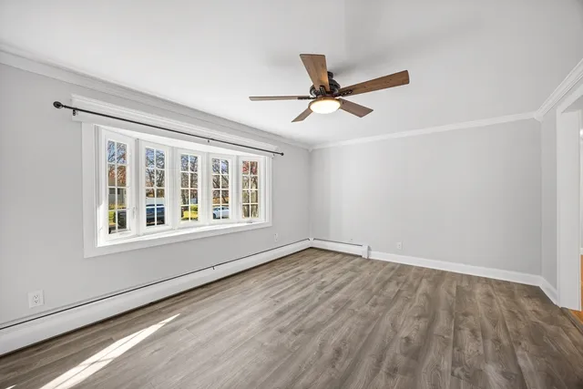 a view of empty room with wooden floor and fan