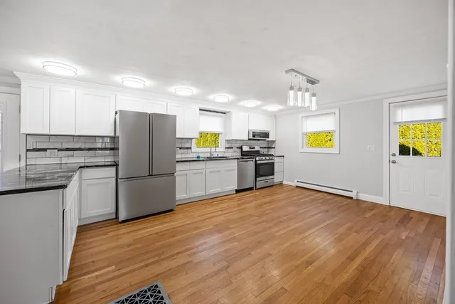 a kitchen with stainless steel appliances a stove a refrigerator a sink a stove top oven and chandelier