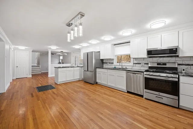 a large kitchen with cabinets wooden floor and stainless steel appliances