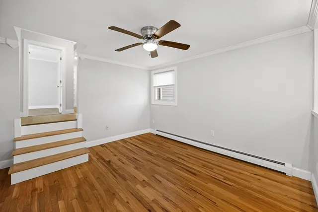 a view of empty room with wooden floor and ceiling fan
