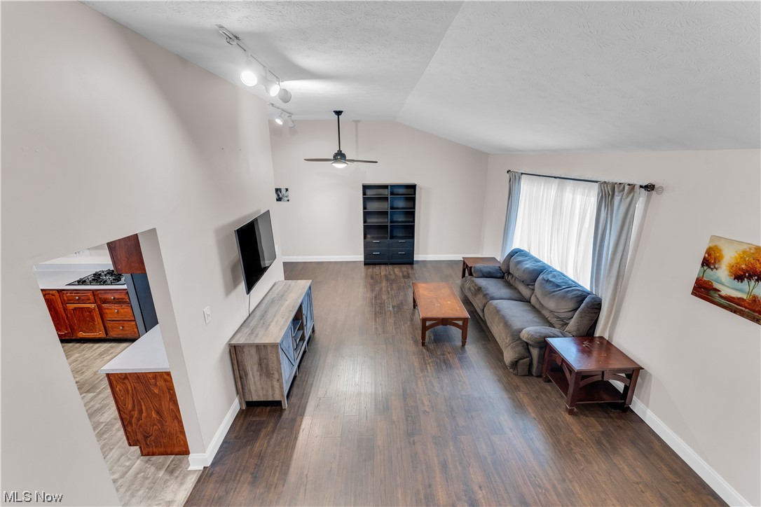 12011 Reno Drive Parma, OH 44130 - Photo 14 of 35 Living room with dark hardwood / wood-style flooring, lofted ceiling, track lighting, and ceiling fan