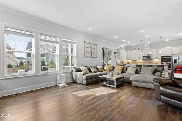 a living room with furniture kitchen view and a wooden floor