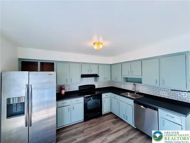 a kitchen with a sink a counter top space cabinets and stainless steel appliances