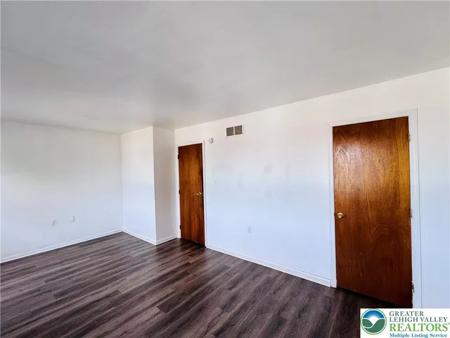 a view of an empty room with wooden floor and closet