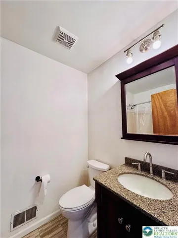 a bathroom with a granite countertop sink vanity mirror and toilet