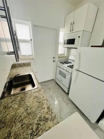 a kitchen with granite countertop white cabinets and a white stove