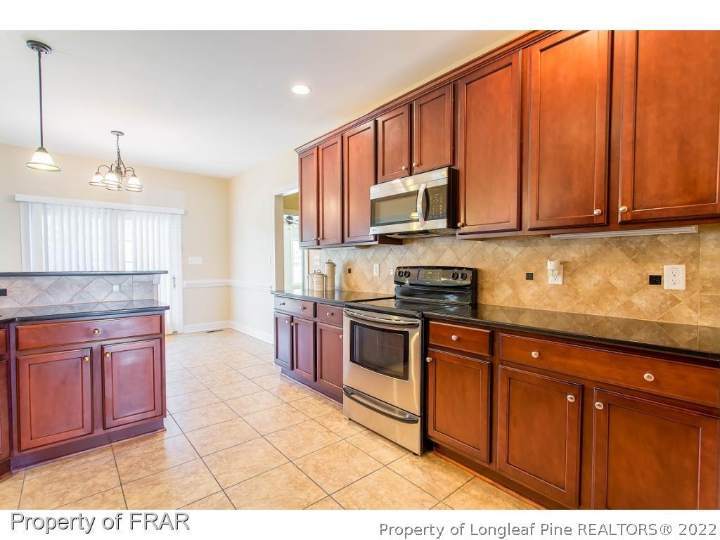 409 St Johns Loop Raeford, NC 28376 - Photo 18 of 36 a kitchen with stainless steel appliances granite countertop a stove a sink and a microwave