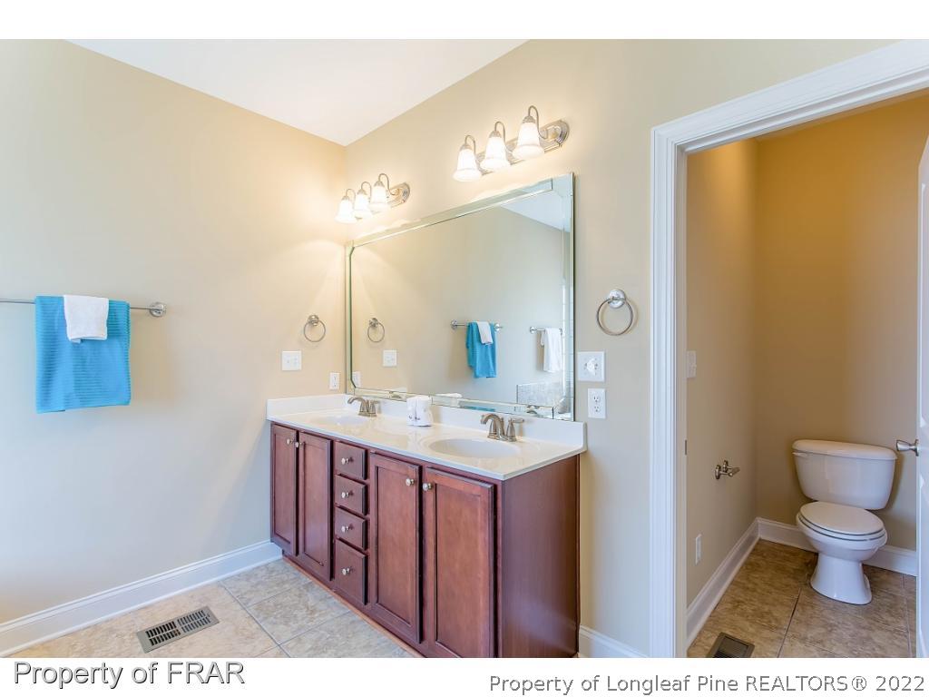 409 St Johns Loop Raeford, NC 28376 - Photo 27 of 36 a bathroom with a toilet a sink a mirror and a shower