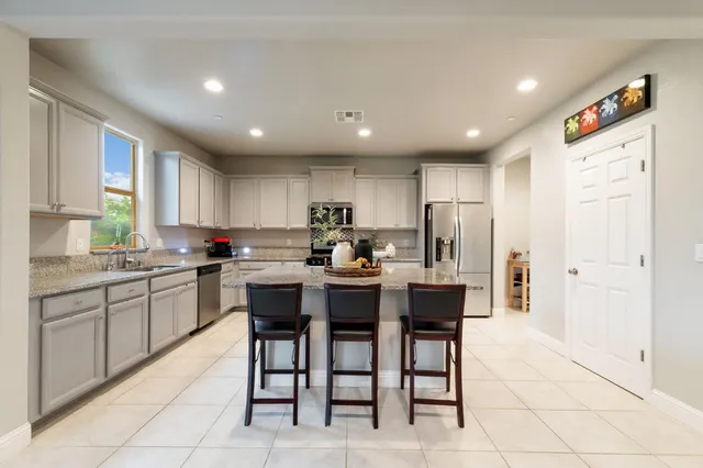 a kitchen with stainless steel appliances kitchen island granite countertop a refrigerator and a stove top oven