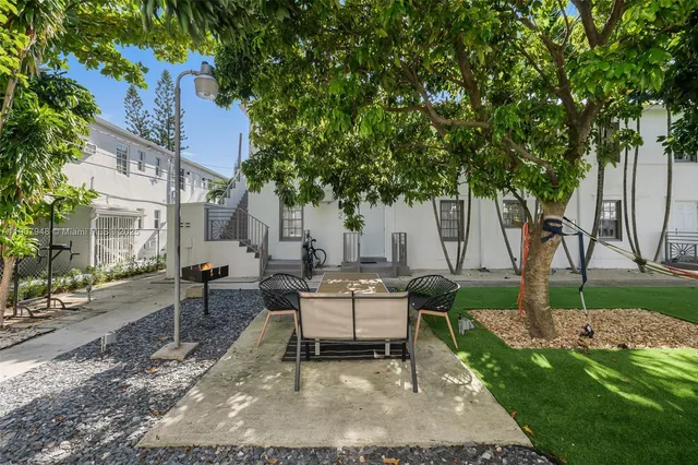 a view of a patio with table and chairs and potted plants and large trees