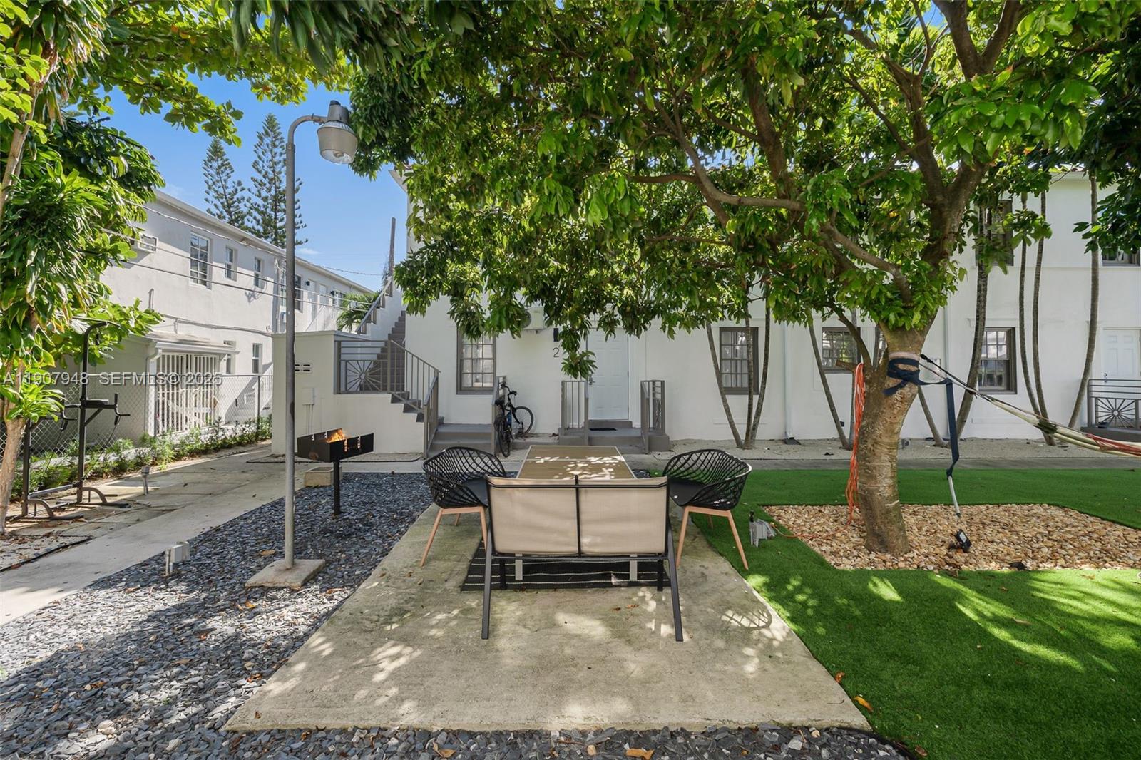 421 75th Street, Unit 3 Miami Beach, FL 33141 - Photo 11 of 21 a view of a patio with table and chairs and potted plants and large trees