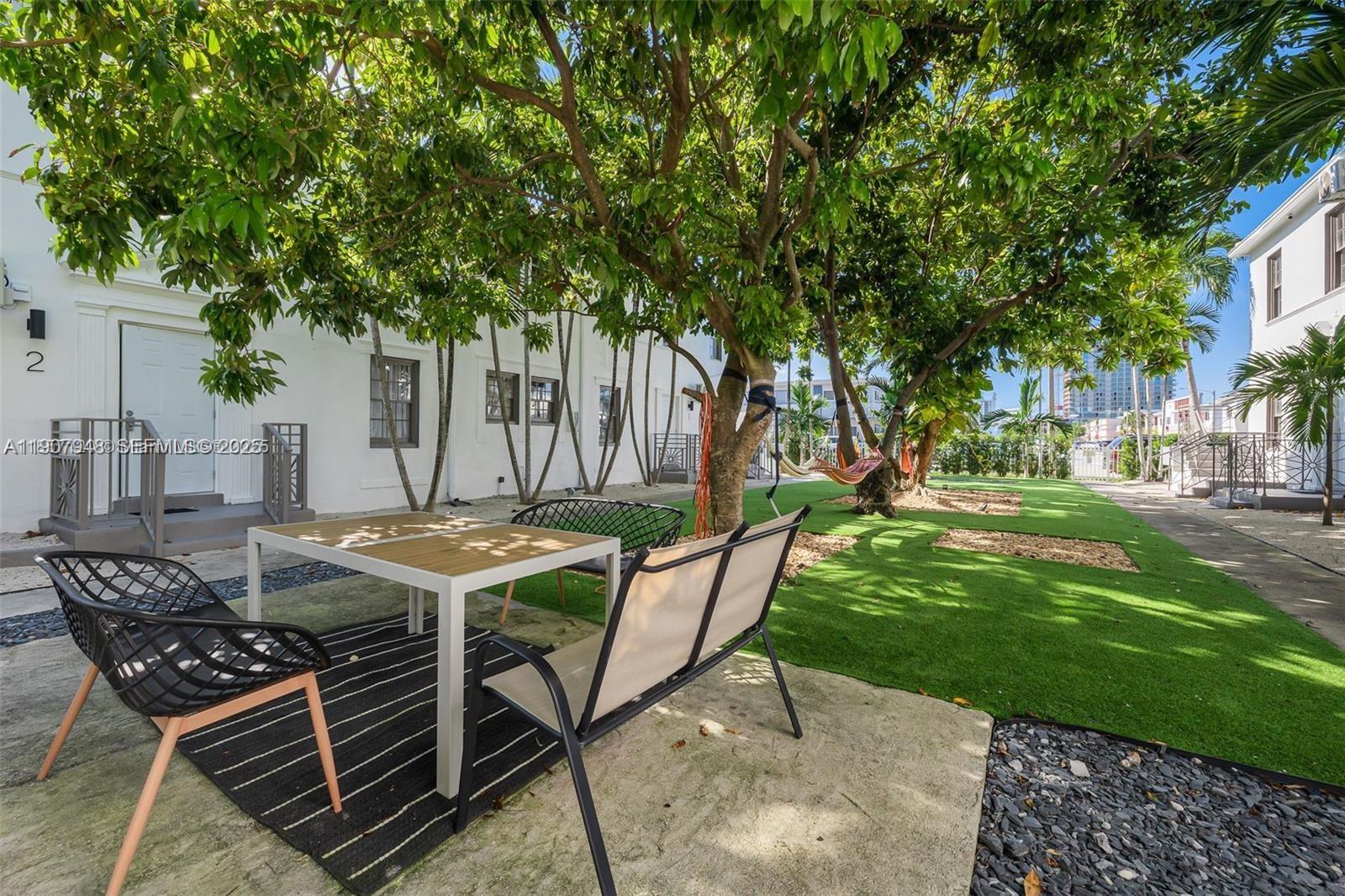 421 75th Street, Unit 3 Miami Beach, FL 33141 - Photo 16 of 21 a view of a patio with table and chairs and potted plants with large trees