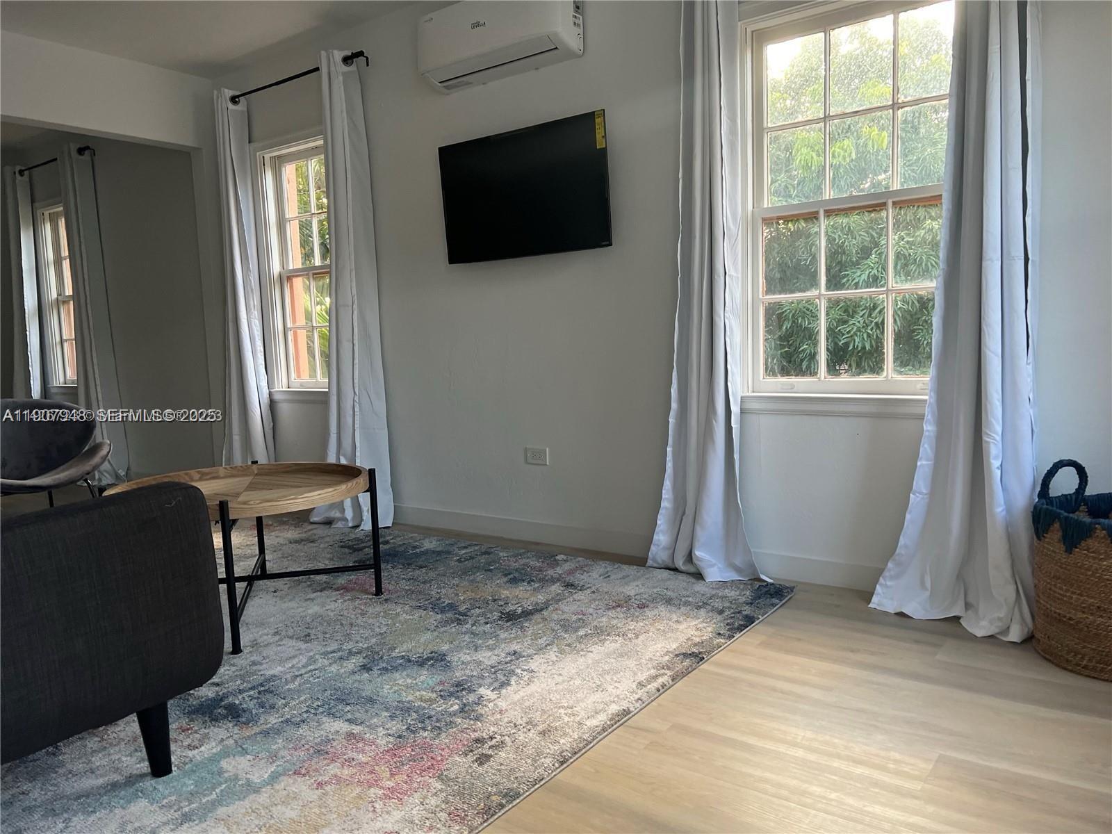 421 75th Street, Unit 3 Miami Beach, FL 33141 - Photo 3 of 21 a living room with a large window and a flat screen tv
