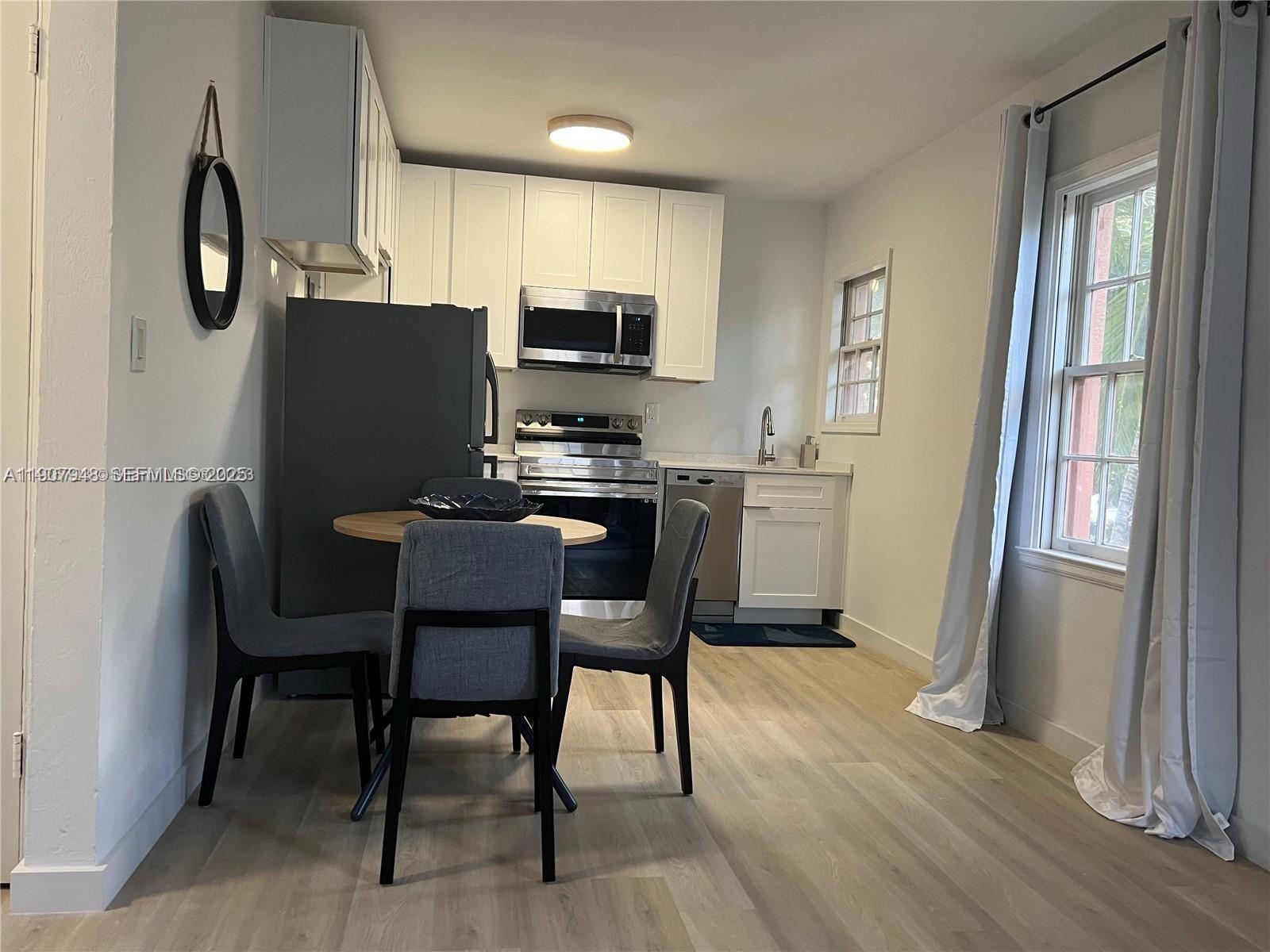 421 75th Street, Unit 3 Miami Beach, FL 33141 - Photo 5 of 21 a kitchen with stainless steel appliances a dining table chairs refrigerator and microwave