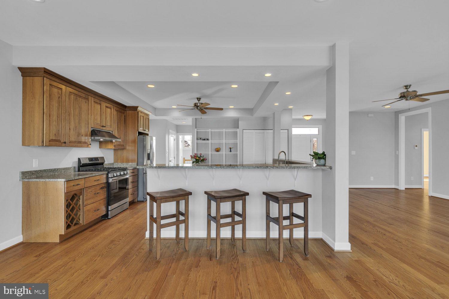 1469 Cowart Road Lottsburg, VA 22511 - Photo 20 of 54 a kitchen with stainless steel appliances kitchen island granite countertop wooden floors and white cabinets