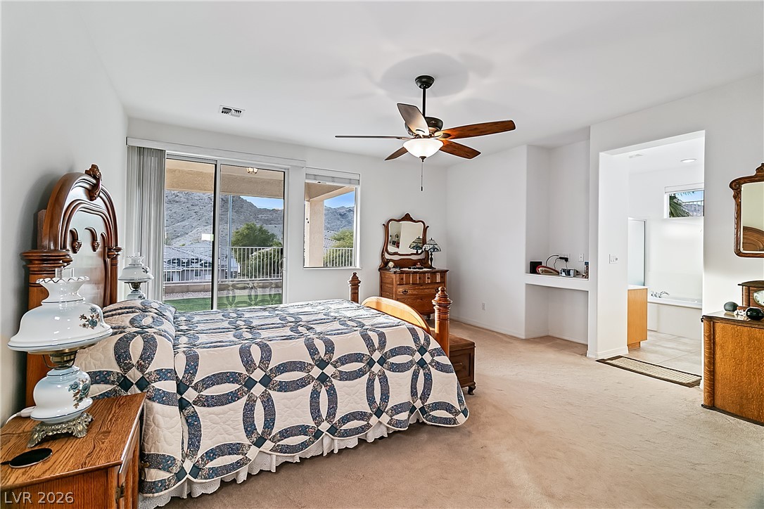 3505 Cottage Meadow Way Laughlin, NV 89029 - Photo 23 of 98 The Primary bedroom has an en-suite primary bathroom, a hobby room, a walk-in closet, and a sliding glass door to the back covered patio.