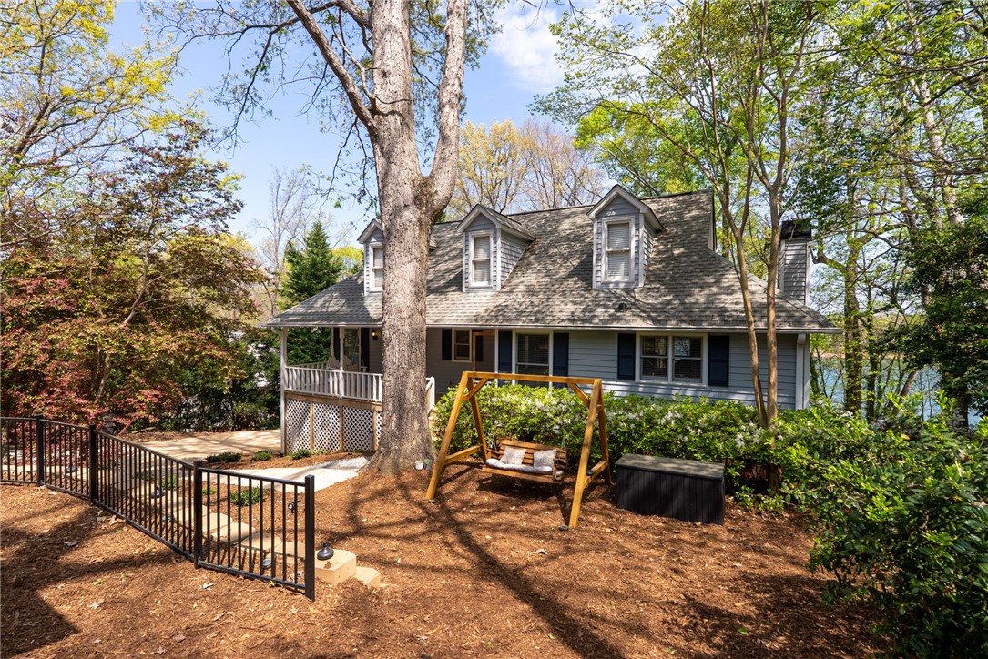 This charming home offers dormer windows, a porch, and a fenced yard with lush landscaping.