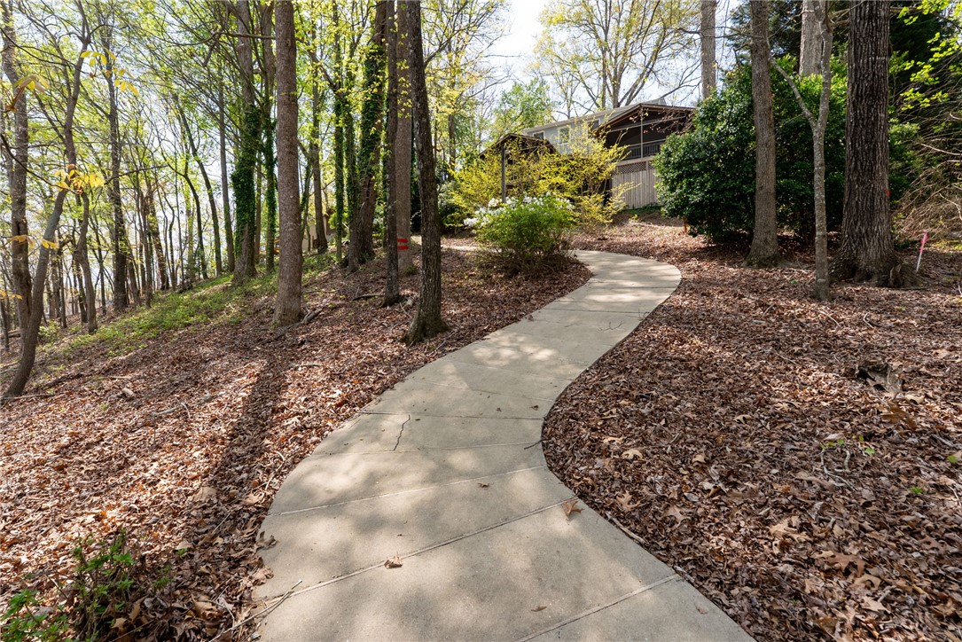 1002 Whitfield Point Road Anderson, SC 29626 - Photo 20 of 49 A winding pathway leads through a tranquil, wooded setting towards a welcoming home.