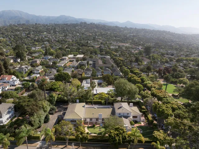 an aerial view of residential houses with outdoor space and trees