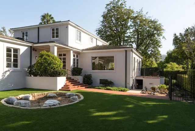 a front view of a house with garden and plants