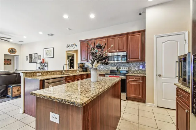 a kitchen with stainless steel appliances granite countertop a stove a sink dishwasher and a microwave oven with large trees