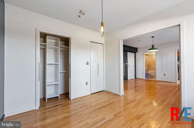 a view of empty room with wooden floor and fan