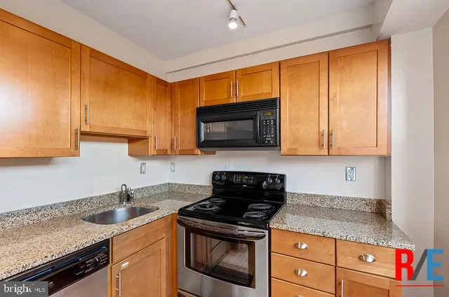 a kitchen with granite countertop wooden cabinets and a stove top oven