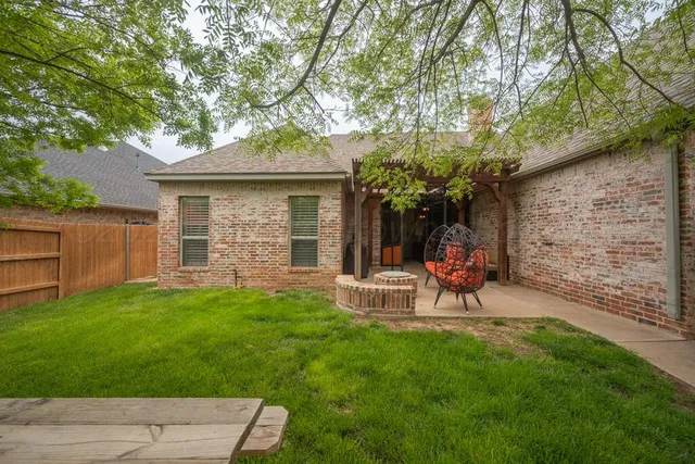 a view of a backyard with table and chairs and a large tree