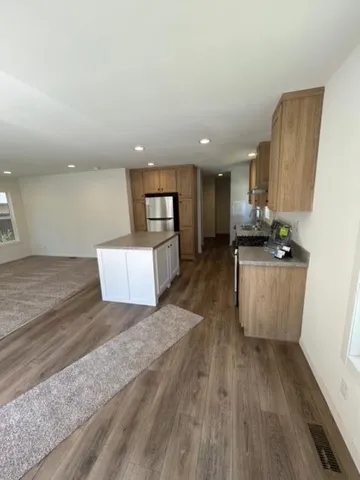 a view of a kitchen with kitchen island wooden floor wooden floor and stainless steel appliances