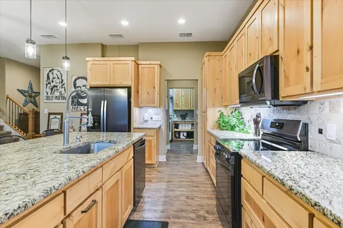 a kitchen with stainless steel appliances granite countertop sink stove refrigerator and cabinets