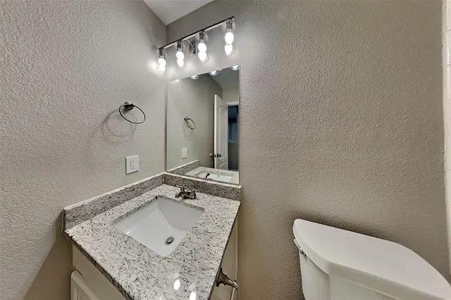 a bathroom with a granite countertop sink a toilet and a mirror