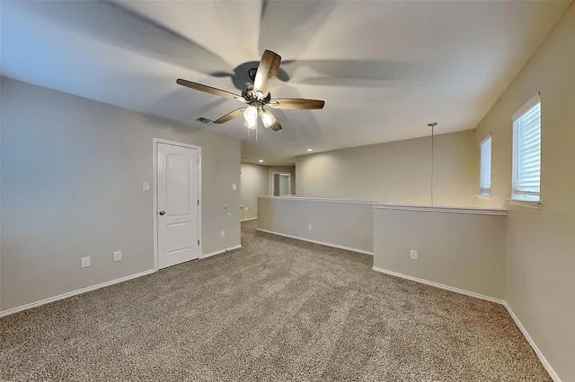 an empty room with chandelier fan and windows