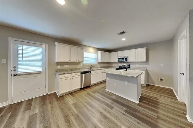 a kitchen with granite countertop a sink cabinets and stainless steel appliances