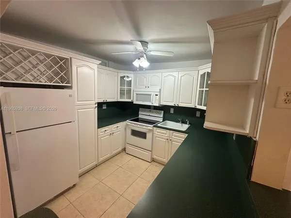 a kitchen with a refrigerator a stove top oven and white cabinets