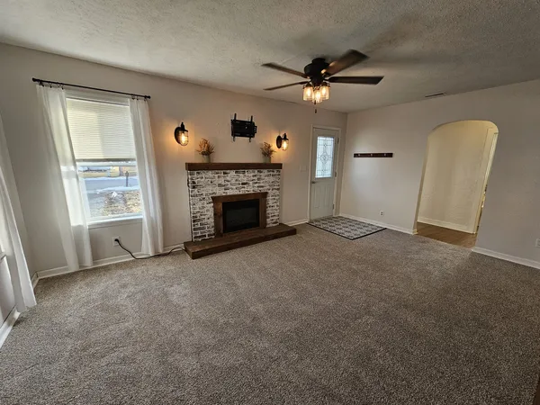 an empty room with windows fireplace and a ceiling fan