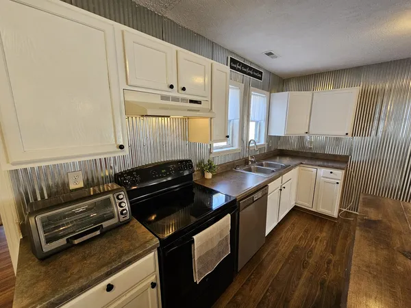a kitchen with stainless steel appliances granite countertop a stove a sink and a microwave