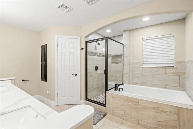 a spacious bathroom with a tub shower and mirror