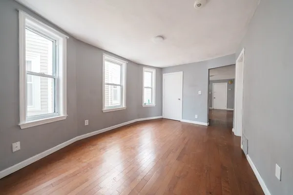 a view of an empty room with wooden floor and a window