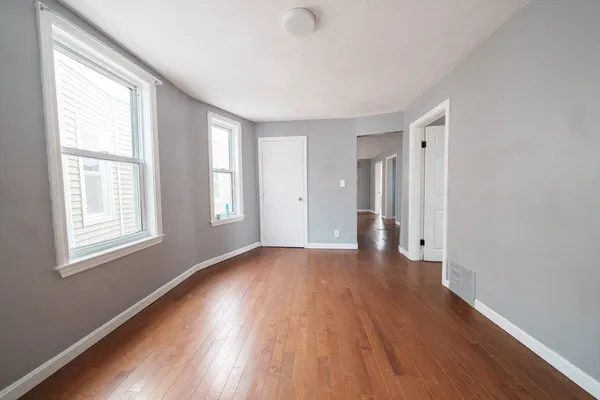 a view of an empty room with wooden floor and a window