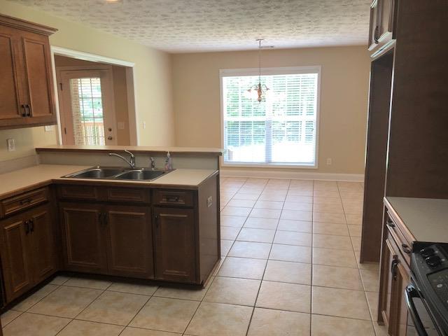 407 Quail Ridge Drive Midland, GA 31820 - Photo 10 of 28 kitchen with stained cabinets and tile floor