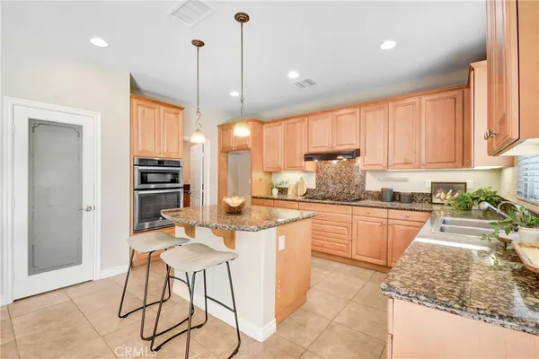 a kitchen with stainless steel appliances granite countertop a stove top oven a sink dishwasher and a refrigerator with wooden floor