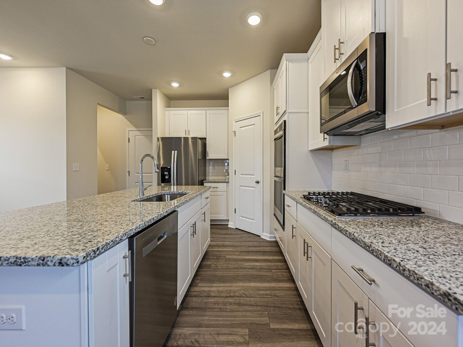 613 Windage Way Pineville, NC 28134 - Photo 2 of 10 a kitchen with stainless steel appliances granite countertop wooden cabinets and a stove top oven