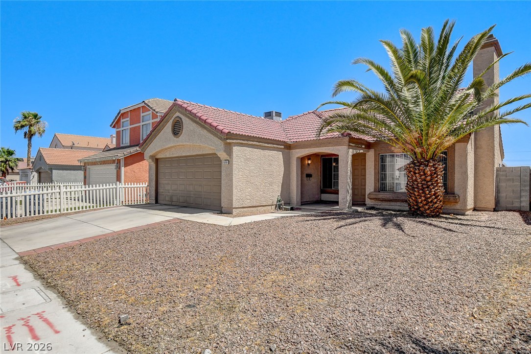 6209 Warm River Road Las Vegas, NV 89108 - Photo 3 of 39 A traditional residence with a red tile roof and a palm tree in the front yard.