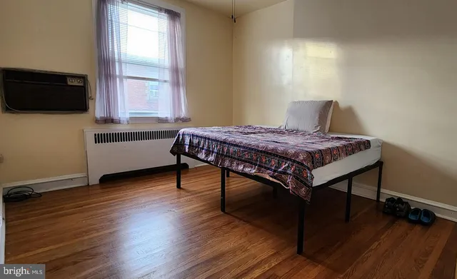 a bedroom with a bed window and wooden floor