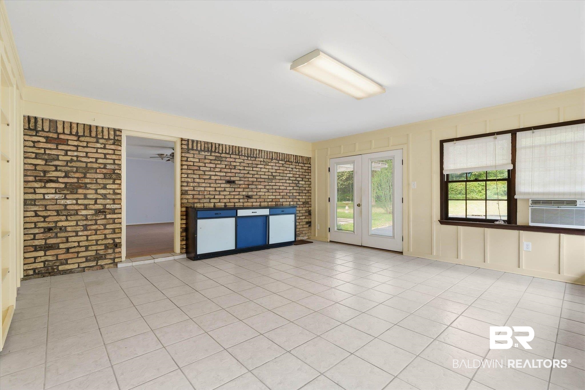 1182 Ginger Drive Mobile, AL 36693 - Photo 27 of 37 Spacious room featuring light-colored tile flooring, exposed brick accents, and a built-in base cabinet