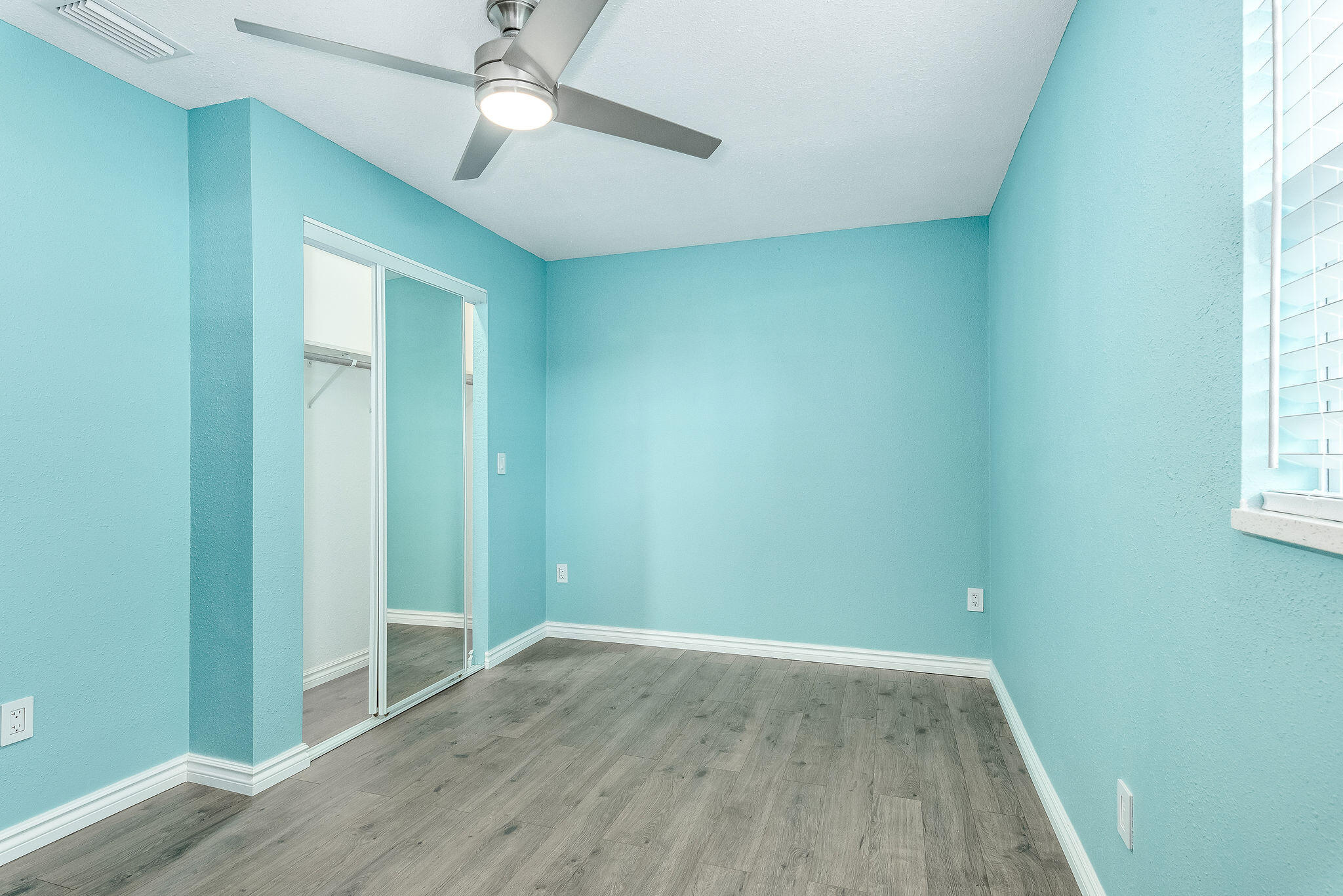 411 4th Street Merritt Island, FL 32953 - Photo 13 of 26 an empty room with wooden floor chandelier fan and windows
