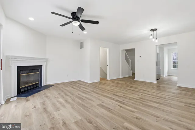 a view of an empty room with a fireplace and a ceiling fan