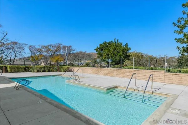 a view of swimming pool with seating space and trees in the background